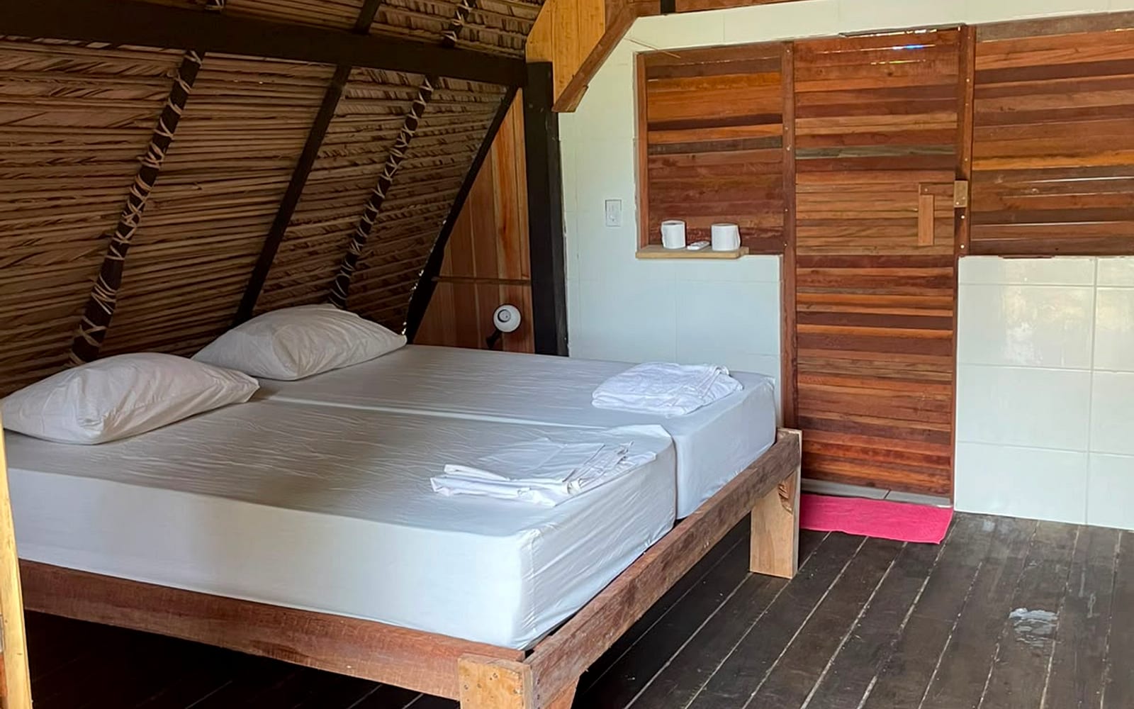 Cama de casal com ar-condicionado e porta do banheiro ao fundo