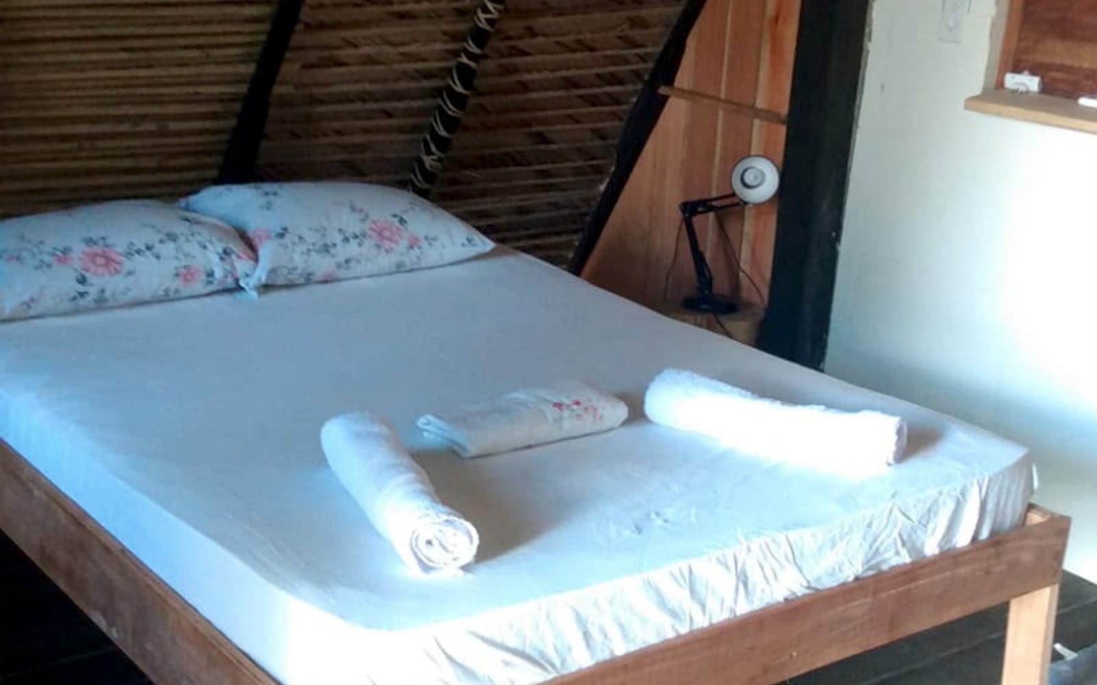 Cama de casal arrumada com toalhas enroladas