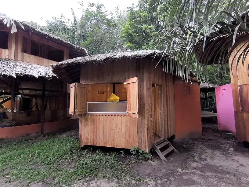 Fachada do Chalé Térreo, com telhado de palha e acesso pelo deck