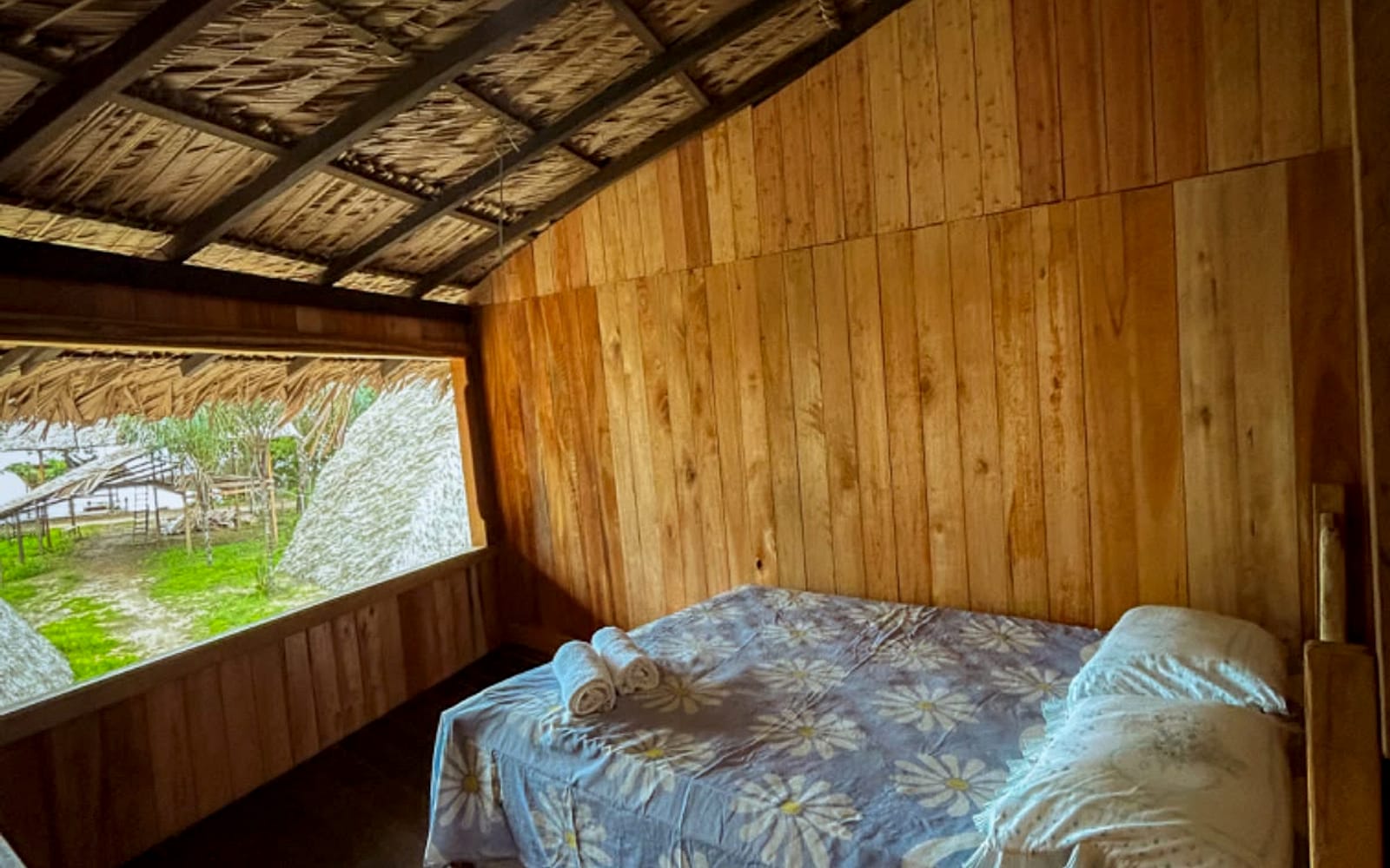 Quarto com janela larga voltada para o pátio e as demais construções da pousada