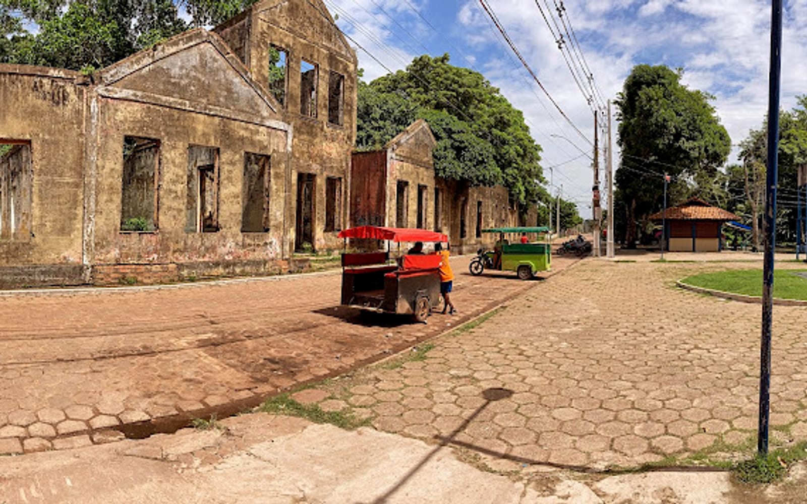 Fachada das ruínas do Educandário à beira da rua, com motorrete estacionada