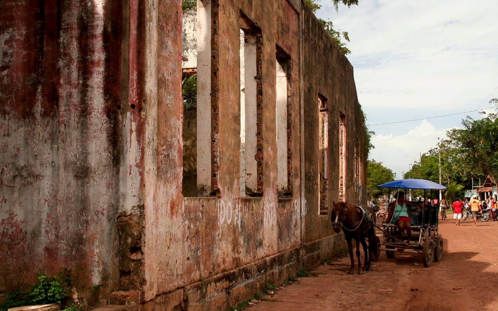Rua de terra na vila de Cotijuba, com charrete e movimento de moradores